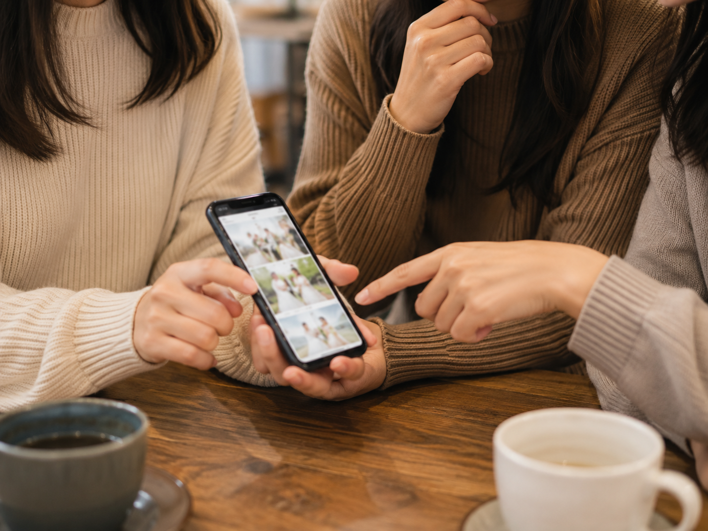 友人同士がスマートフォンを見ながら結婚式の話をする口コミ・紹介のイメージ写真